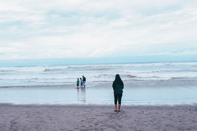 Rear view of people on beach against sky