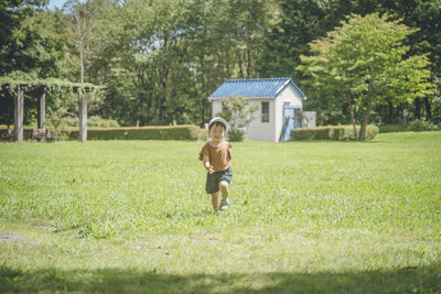 Side view of boy playing with dog on grassy field