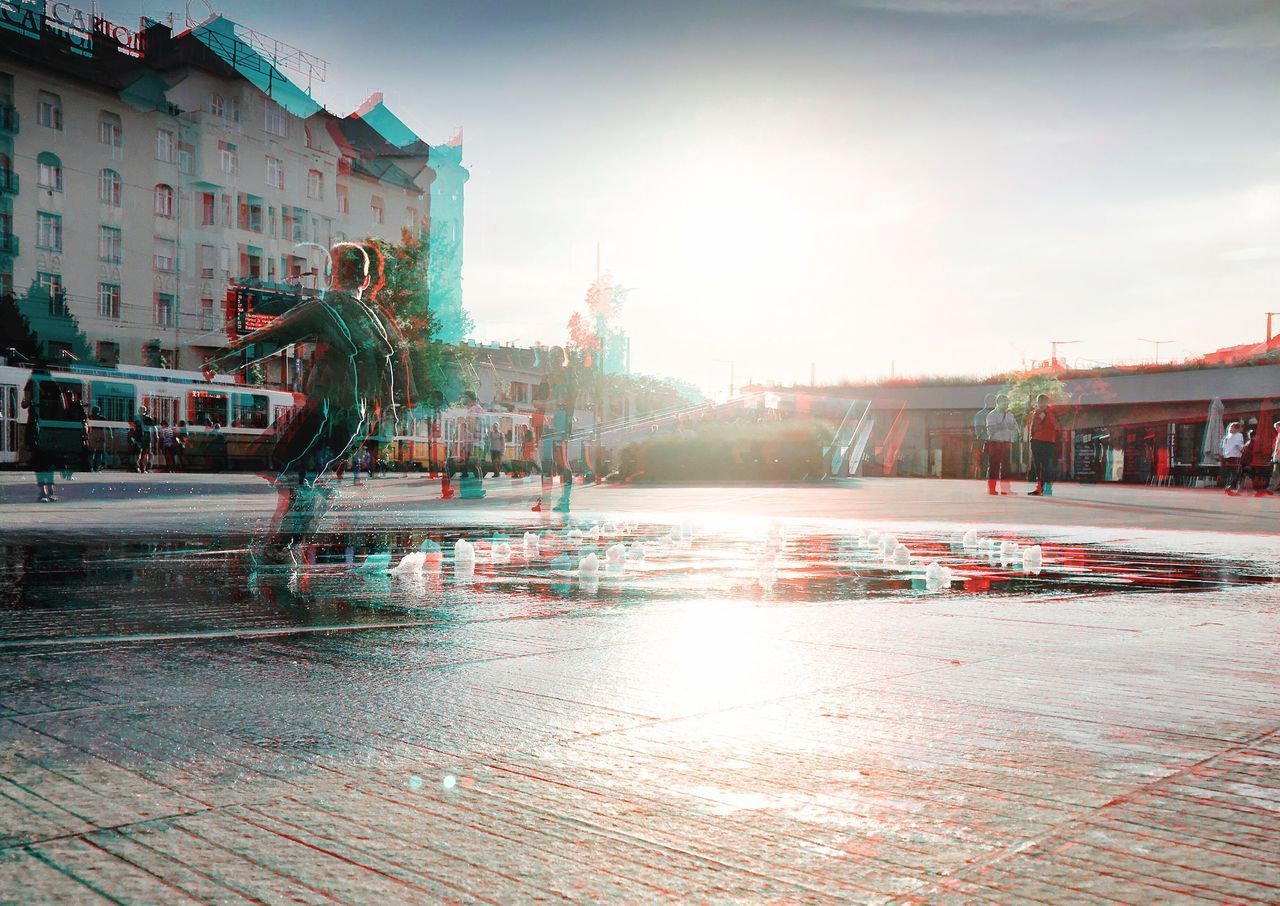 WET STREET AMIDST BUILDINGS AGAINST SKY