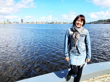 Portrait of smiling young woman standing against sky