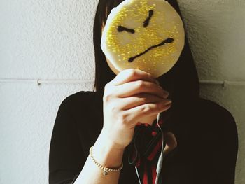 Midsection of woman holding angry face against wall