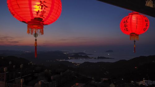 Low angle view of illuminated lanterns hanging against sky