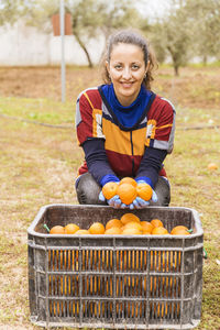 Portrait of smiling woman holding oranges in basket