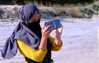 Woman  photographing with mobile phone wearing hijab