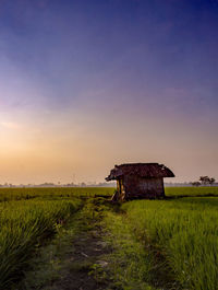 Abandoned barn on field against sky during sunset