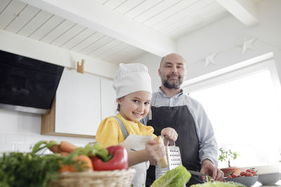 Happy friends standing by people in kitchen