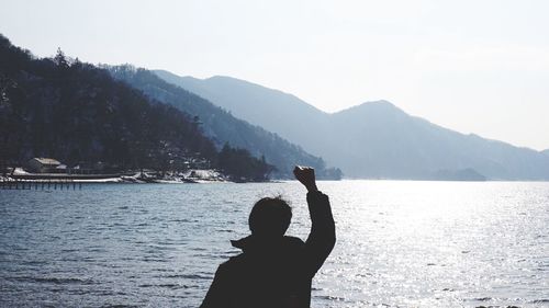 Rear view of man at lake against mountains