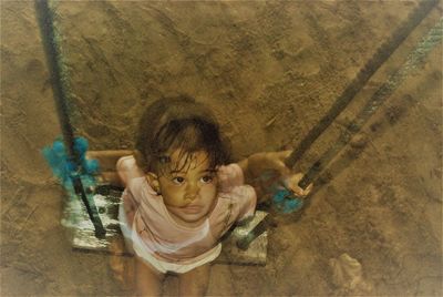 Double exposure image of girl sitting on swing outdoors