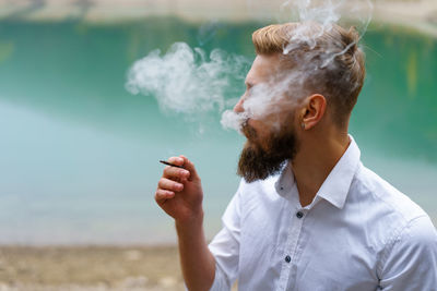 Young man beard smokes cigarette or tobacco. guy is addicted to cigarettes