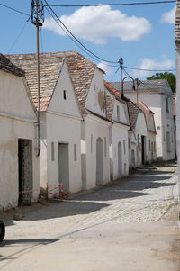 Empty street amidst houses against sky