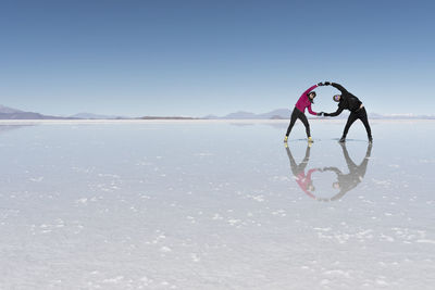 Couple holding hands while standing on salt flat