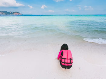 Rear view of woman sitting on beach
