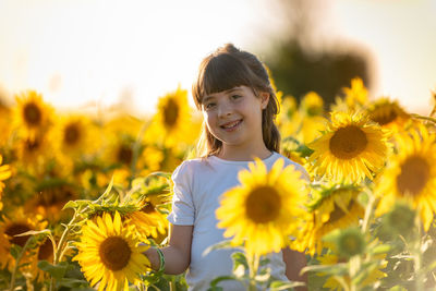 Portrait of girl with yellow flowers on field