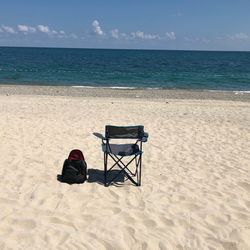 Chair on shore at beach against sky