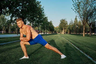 Full length of shirtless man sitting in park