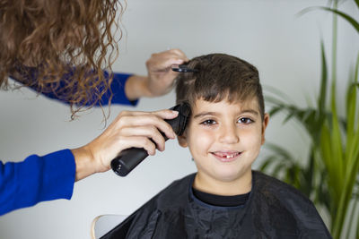 Mother cutting her son's hair at home