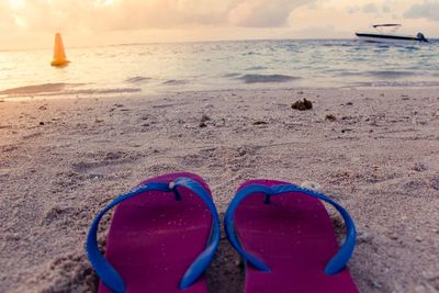 Deck chairs on beach against sky during sunset