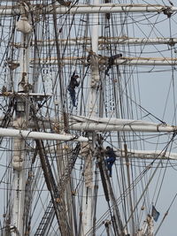 Low angle view of workers on ship against clear sky