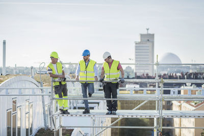 Architects and construction worker discussing on scaffolding at site