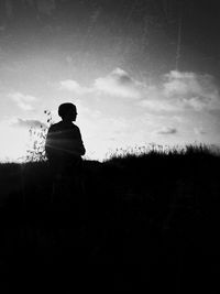 Rear view of silhouette man standing on field against sky