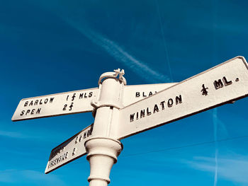 Low angle view of road sign against blue sky