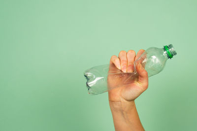 Close-up of hand holding glass against blue background