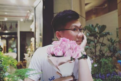 Thoughtful young man holding roses in flower shop