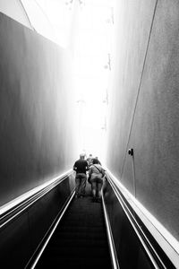 Low angle view of people on escalator amidst walls