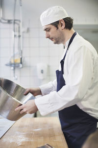 Side view of male baker working in commercial kitchen