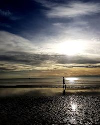 Silhouette man standing on beach against sky during sunset