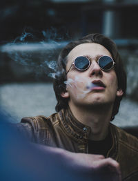 Close-up of man wearing sunglasses exhaling smoke