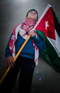 Low section of child holding red standing against wall