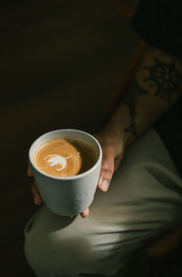 Midsection of woman holding coffee on table