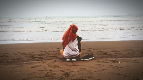 Rear view of woman on beach against sky
