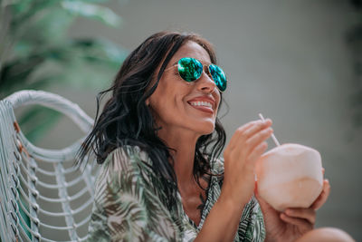 Portrait of a smiling young woman wearing sunglasses outdoors