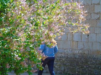 Rear view of woman with cropped flower tree in foreground