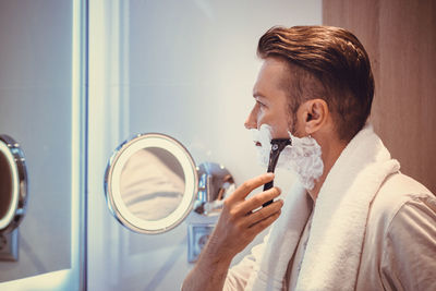 Side view of mature man shaving at home