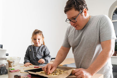 Father making cookies with daughter at home