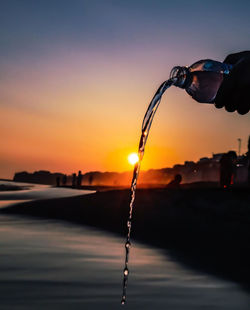 Close-up of water splashing against sky during sunset