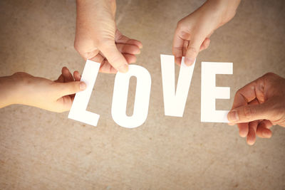 Close-up of human hands holding the word "love"