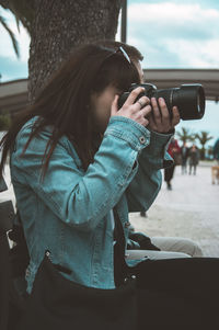 Side view of a woman photographing camera