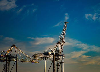 Low angle view of crane at construction site against sky