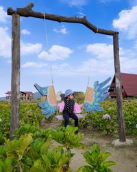 Rear view of woman with umbrella against sky