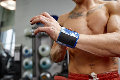 Midsection of shirtless man exercising in gym