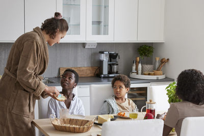 Family sitting at table and eating breakfast