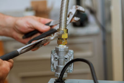 Close-up of cropped hands repairing machine at workshop