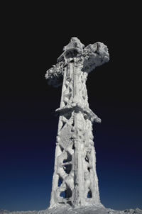 Low angle view of cross on snow against sky