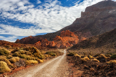 Road leading towards mountains against sky