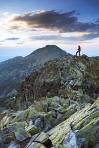 Man standing on rock against sky