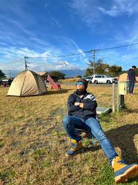 Rear view of man standing on field against sky